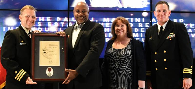 (DAHLGREN, Va. (May 10, 2019) – Robert Parker holds the Paul J. Martini Award moments after receiving it from Naval Surface Warfare Center Dahlgren Division (NSWCDD) leadership at the command’s annual honor awards ceremony. Parker was recognized for providing flawless executive assistance to the NSWCDD Dam Neck Activity commanding officer. Standing left to right: NSWCDD Dam Neck Activity Commanding Officer Cmdr. Andrew Hoffman; Parker; NSWCDD Deputy Technical Director Angela Beach; and NSWCDD Commanding Officer Cmdr. Stephen ‘Casey’ Plew.  (U.S. Navy photo/Released)