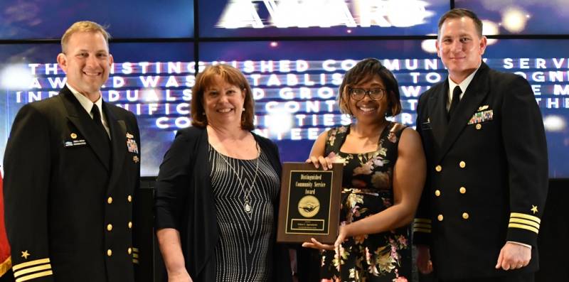 DAHLGREN, Va. (May 10, 2019) – Feline Agwumezie holds the Distinguished Community Service Award moments after receiving it from Naval Surface Warfare Center Dahlgren Division (NSWCDD) leadership at the command’s annual honor awards ceremony. Agwumezie was recognized for her contribution to improving the community through service and outreach. Her work with children and the less fortunate serves as an example of volunteerism and the spirt that embodies Dahlgren Division’s commitment to the community. Standing left to right: NSWCDD Dam Neck Activity Commanding Officer Cmdr. Andrew Hoffman; NSWCDD Deputy Technical Director Angela Beach; Agwumezie; and NSWCDD Commanding Officer Cmdr. Stephen ‘Casey’ Plew.  (U.S. Navy photo/Released) 