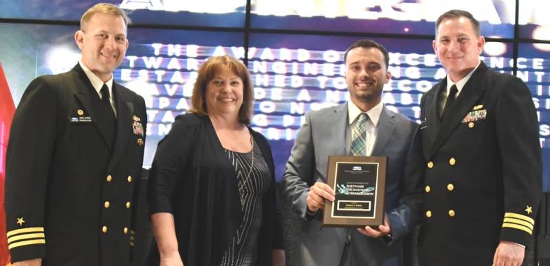 DAHLGREN, Va. (May 10, 2019) – Zachary Mohle holds the Award of Excellence for Software Engineering and Integration moments after receiving it from Naval Surface Warfare Center Dahlgren Division (NSWCDD) leadership at the command’s annual honor awards ceremony. Mohle was recognized for rapidly developing new software capabilities for emergent warfighter requirements. His exceptional performance led to the delivery of a versatile capability that improves the Navy’s understanding of environmental impacts in its areas of responsibility and supports other operational platforms and missions. Standing left to right: NSWCDD Dam Neck Activity Commanding Officer Cmdr. Andrew Hoffman; NSWCDD Deputy Technical Director Angela Beach; Mohle; and NSWCDD Commanding Officer Cmdr. Stephen ‘Casey’ Plew.  (U.S. Navy photo/Released)  