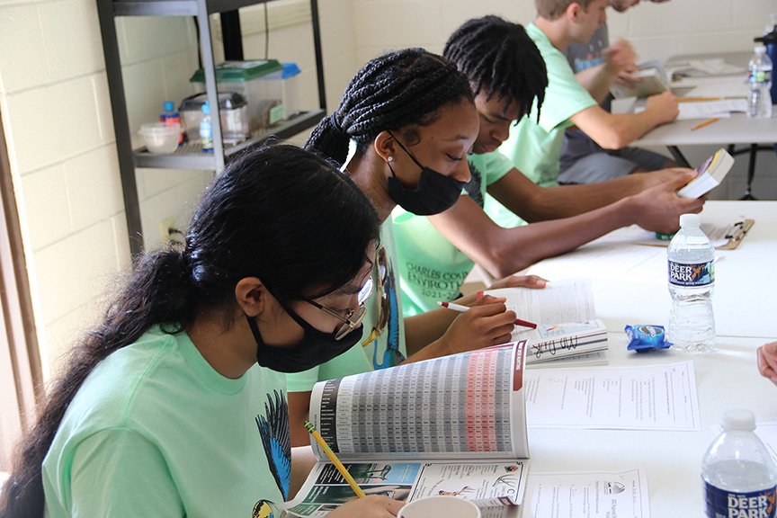 North Point High School students Kelsie Luna, junior, left, and sophomores Zanyah Harris and Brandon Riley use field guides and other materials to find the correct answers to questions during the wildlife portion of the Charles County Envirothon.