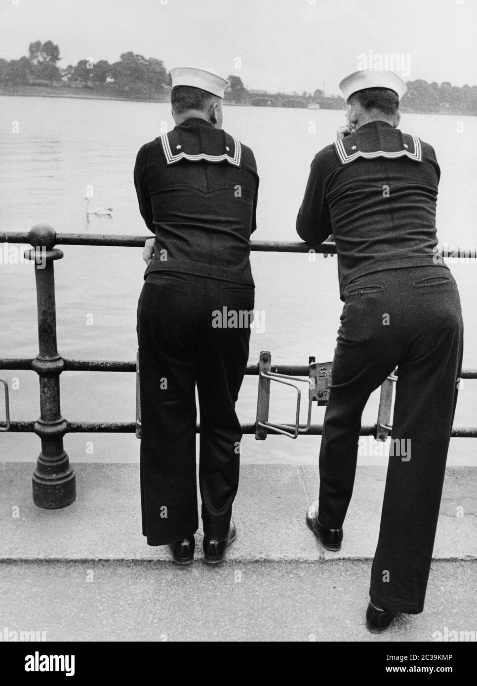 two-us-navy-sailors-lean-against-a-railing-and-look-across-the-binnenalster-to-the-lombardsbru...jpg